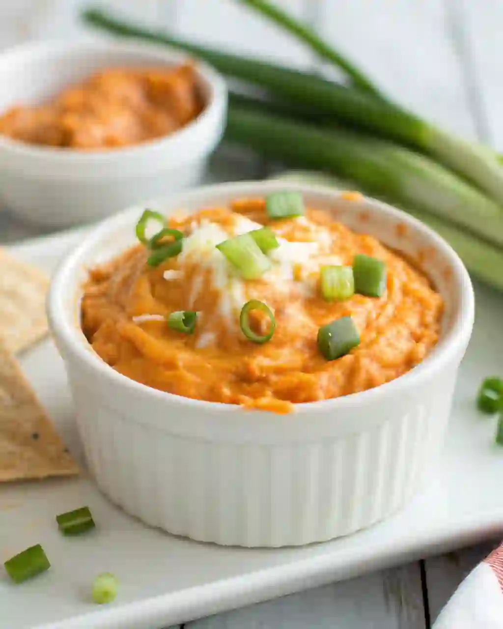 Creamy buffalo chicken dip in a white ramekin topped with green onions